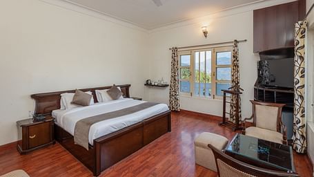 Shot of a spacious guest room at DLS Tehri Club Resort with a king size bed and a sitting area.